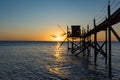 A fishing hut called carrelet with craft lifting net at sunset. Esnandes, charente maritime, France. The sun is caught in the net