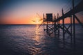 A fishing hut called carrelet with craft lifting net at sunset. Esnandes, charente maritime, France. The sun is caught in the net