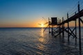 A fishing hut called carrelet with craft lifting net at sunset. Esnandes, charente maritime, France. The sun is caught in the net