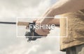 Fishing inscription sign on photo of male hands with reel rod in hands on sunny summer day