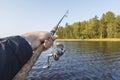 Fishing on a lake. Fishing rod with a reel in hand Royalty Free Stock Photo