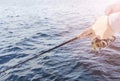 Fishing on the lake. Hands of fisherman with fishing rod and reel. Macro shot. Fishing rod and hands of fisherman over lake water Royalty Free Stock Photo