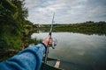 Fishing on a lake at sunset. Fishing rod with a reel in hand Royalty Free Stock Photo