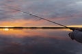 Fishing on the lake at the sunset. Hands of fisherman with fishing rod. Macro shot. Fishing rod and hands of fisherman over lake w Royalty Free Stock Photo