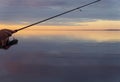 Fishing on the lake at the sunset. Hands of fisherman with fishing rod. Macro shot. Fishing rod and hands of fisherman over lake w Royalty Free Stock Photo