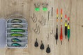 Fishing lure and fishhooks, weight, bell and float on the wooden table