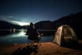 Fishing Man is Sitting at Night by Lake, Fishing Chair, Outdoor Tent, Fisherman Holds a Fishing Rod Royalty Free Stock Photo