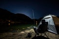Fishing Man is Sitting at Night by Lake, Fishing Chair, Outdoor Tent, Fisherman Holds a Fishing Rod Royalty Free Stock Photo