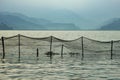 Fishing net over the lake water on the background of blurry mountains in the fog in the evening Royalty Free Stock Photo