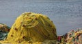 Fishing net yellow pile on port drying under the sun, blue sea background. Greece Cyclades island Royalty Free Stock Photo