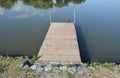 A small fishing pier made of wooden boards above the pond by the river lake is used for comfortable fishing or mooring of a boat, Royalty Free Stock Photo