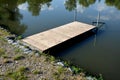 a small fishing pier made of wooden boards above the pond by the river lake is used for comfortable fishing or mooring of a boat, Royalty Free Stock Photo