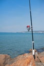Fishing pole with red reel on blue sea Royalty Free Stock Photo