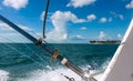 Fishing poles on deep sea fishing boat with view of island in distance under blue skies with fluffy white clouds Royalty Free Stock Photo