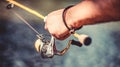 Fisherman hand holding fishing rod with reel. Fishing Reel. Fishing Rod with Aluminum Body Spool. Fishing Gear. Fish Royalty Free Stock Photo