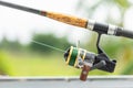 Fishing reel and rod in fisherman hand in a pond