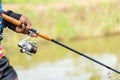 Fishing reel and rod in fisherman hand in a pond