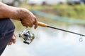 Fishing reel and rod in fisherman hand in a pond Royalty Free Stock Photo