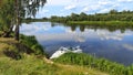 Fishing on the river in summer. A plastic motorboat is moored to the sandy shore. Nearby a feeder rod for bream fishing is set up. Royalty Free Stock Photo