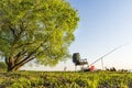 Fishing rod and fishing chair under large green tree on beautiful shore of lake or river on warm summer evening. summer fishing Royalty Free Stock Photo