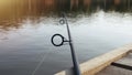 Fishing rod over lake water, lying on wood jetty Royalty Free Stock Photo