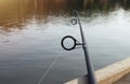 Fishing rod over lake water, lying on wood jetty Royalty Free Stock Photo