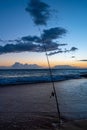 A fishing rod on a sandy beach on a pacific ocean background at the sunset in Maui, Hawaii Royalty Free Stock Photo