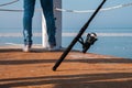 Fishing rod spinning leaning on a white barrier on the pier with blue sky and sea background Royalty Free Stock Photo