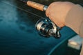 Fishing rod with a spinning reel in the hands of a fisherman. Royalty Free Stock Photo