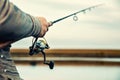 Fishing rod with a spinning reel in the hands of a fisherman Royalty Free Stock Photo