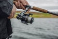 Fishing rod with a spinning reel in the hands of a fisherman on an overcast spring day. Royalty Free Stock Photo