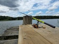 A fishing rod on a wooden bridge by the lake. Royalty Free Stock Photo
