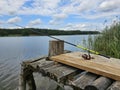 A fishing rod on a wooden bridge by the lake. Royalty Free Stock Photo