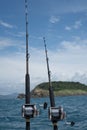 Fishing rods on a boat over blue sea, sky and green island Royalty Free Stock Photo