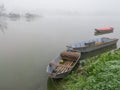 Fishing row boats and fisherman`s huts in deep autumn fog. Royalty Free Stock Photo