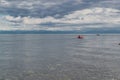 Fishing small red boat with people floats in silver clean lake baikal, in the morning against the background of blue mountains Royalty Free Stock Photo