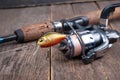 Fishing spinning reel and fishing lures on wooden table