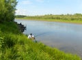 Fishing summer fine afternoon. Landscape with river, green grass, clear sky