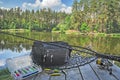 Fishing tackle set. Spinning rod with reel and lures on wooden platform on forest lake background Royalty Free Stock Photo