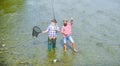 Fishing team. Male friendship. Father and son fishing. Summer weekend. Fishing together. Men stand in water. Nice catch