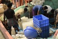 Fishing trawler crew preparing voyage supplies with ice blocks for cargo preservation at Frezarganj Harbor, West Bengal, India