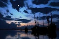 fishing trawlers silhouette framed by moonlit clouds at dusk