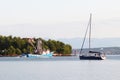 The fishing vessel for squid extraction returns in the early morning sailing past the green shore and sailing yacht. Catch of