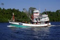 Fishing vessel underway at sea over blue sky and sea