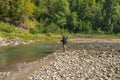 Fishing at wild mountain river. Fisherman catch trout fish at stone coast of forest stream Royalty Free Stock Photo