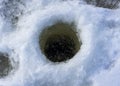 Fishing in the winter. Fishermen drilled a hole in the ice of a lake or river. Close up view. Snow ice background Royalty Free Stock Photo
