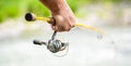 Fishings reel close-up on the background of the river. Fisherman hand holding fishing rod with reel. Fishing Reel Royalty Free Stock Photo