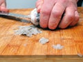 Fishmonger cleaning raw uncooked sea bream on wooden board with sharp knife. Scales on the board, belly cutting stage