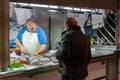 fishmonger preparing fresh fish for a waiting customer in the indoor market in Alicante