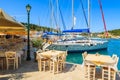 FISKARDO PORT, KEFALONIA ISLAND, GREECE - SEP 16, 2014: restaurant tables in typical Greek tavern and yacht boats in Fiskardo port